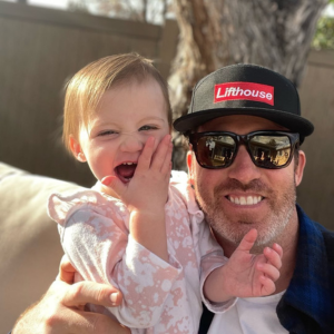 Dr. Andrew Chappell with a smiling baby outdoors in West Jordan.